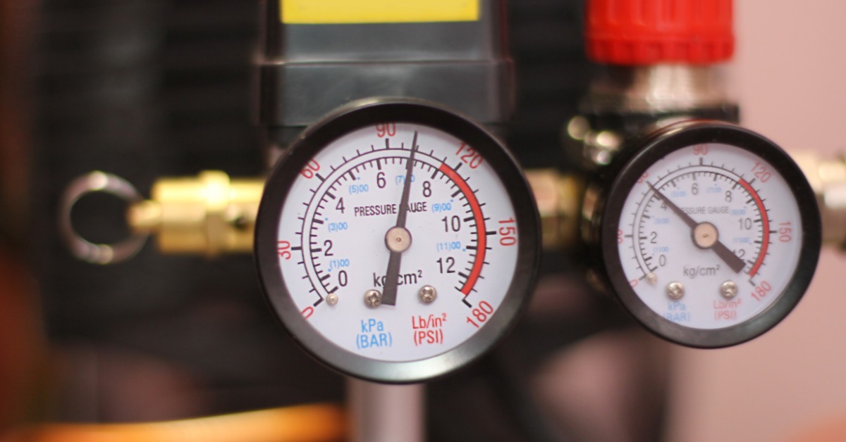 Two round analog pressure gauges with black rims, white numbered dials, and metal fittings on industrial equipment.