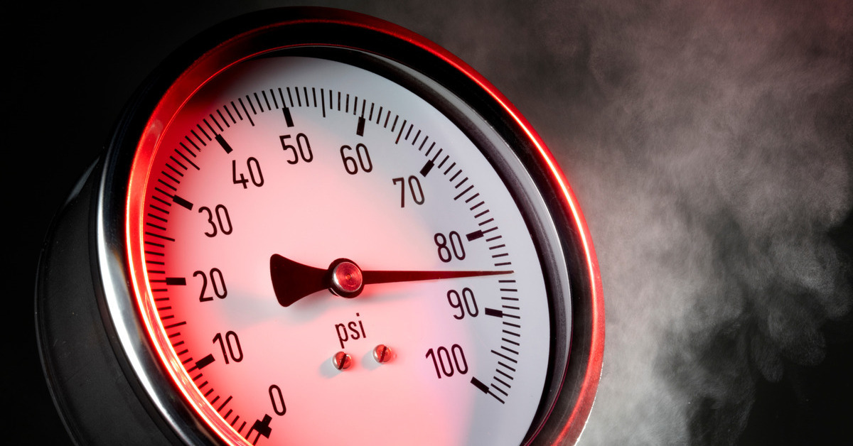 An up-close view of a pressure gauge with smoke in the background. The meter reads 86 PSI and measures from 0 to 100.