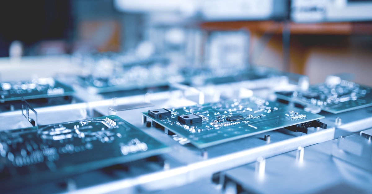 A circuit board showing electronic microcircuits and solder connections at a manufacturing facility.