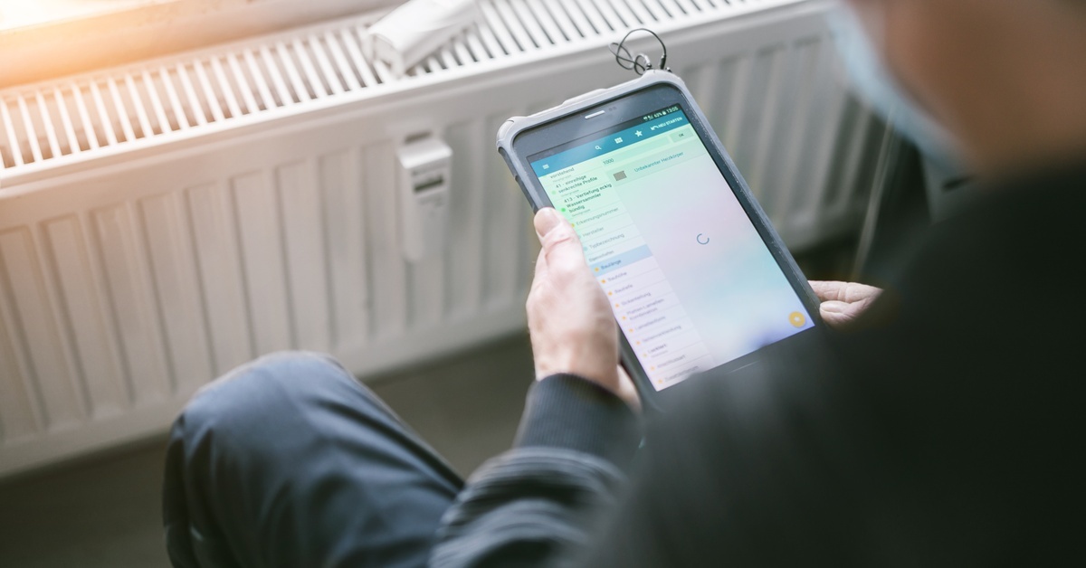 A close-up of a person using a tablet to adjust the thermometer settings on the large heater in front of them. A close-up of a person using a tablet to adjust the thermometer settings on the large heater in front of them.