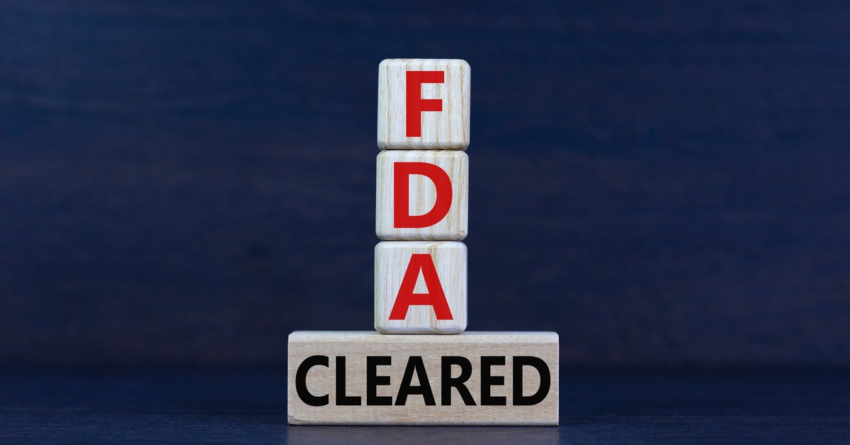 Wooden blocks spelling out "FDA cleared," with three small cubes stacked vertically atop a single long horizontal block.